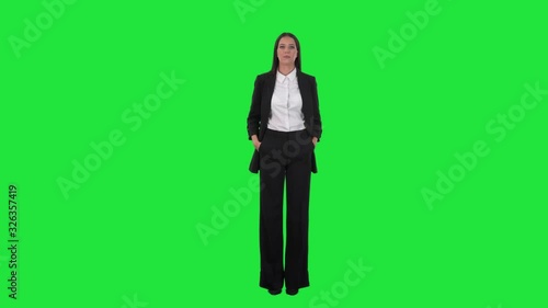 Serious and happy version of young elegant business woman turning from side view at camera. Full body on chroma key green screen background.