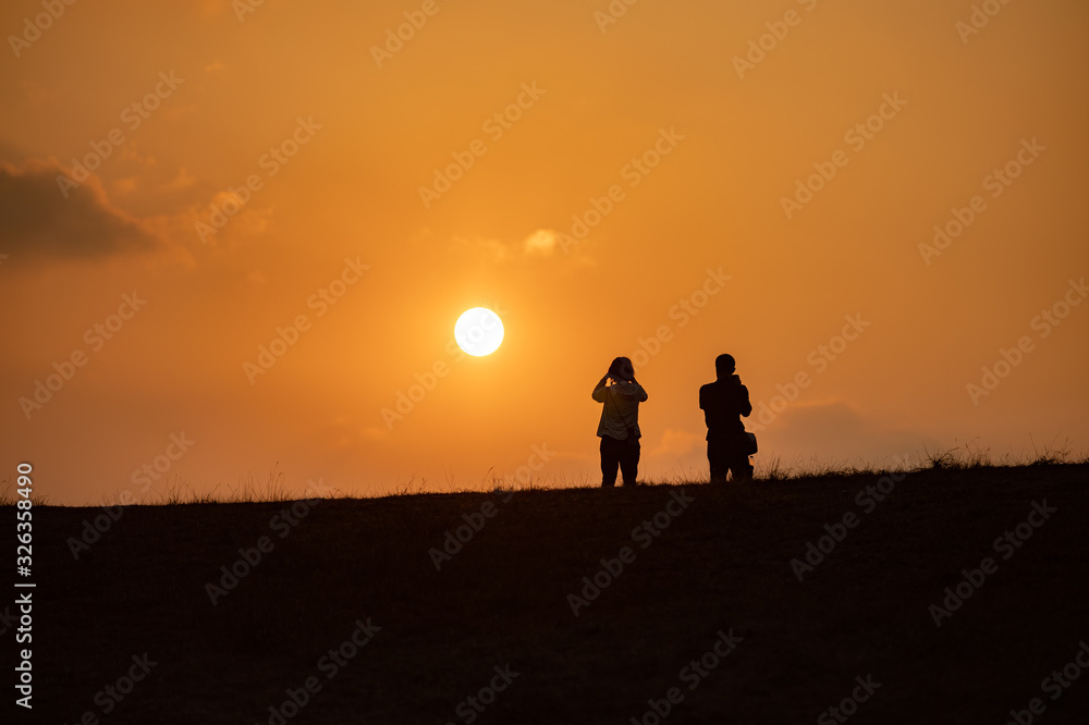 2 people standing and see sunset orange color