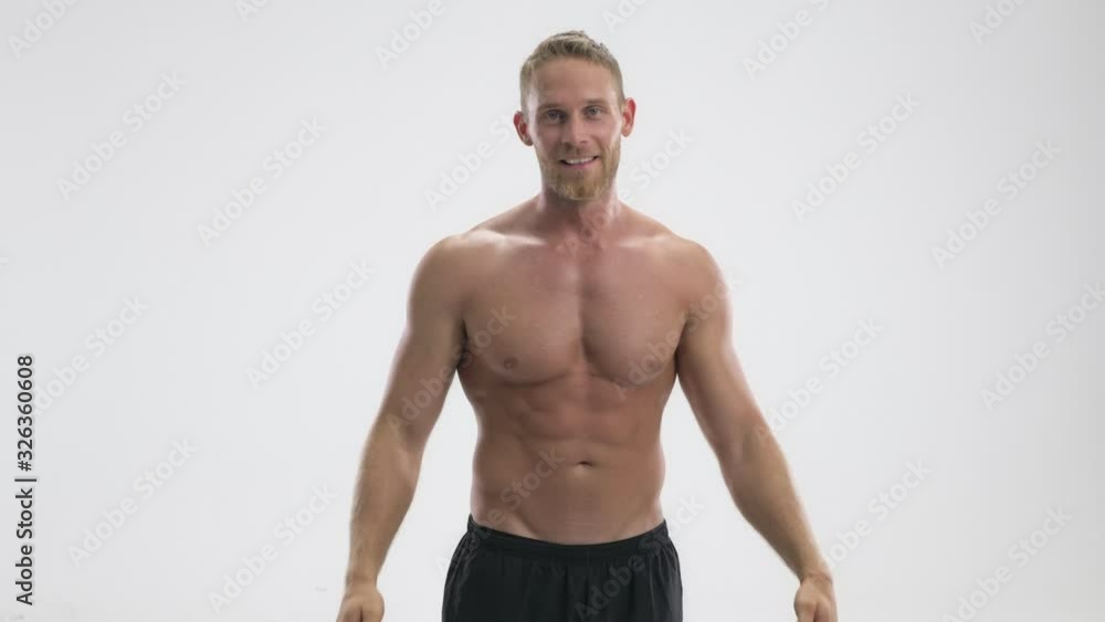 A strong young shirtless sportsman is showing his biceps while raising his hands isolated over white background A strong young shirtless sportsman is showing his biceps while raising his hands isolated over white background