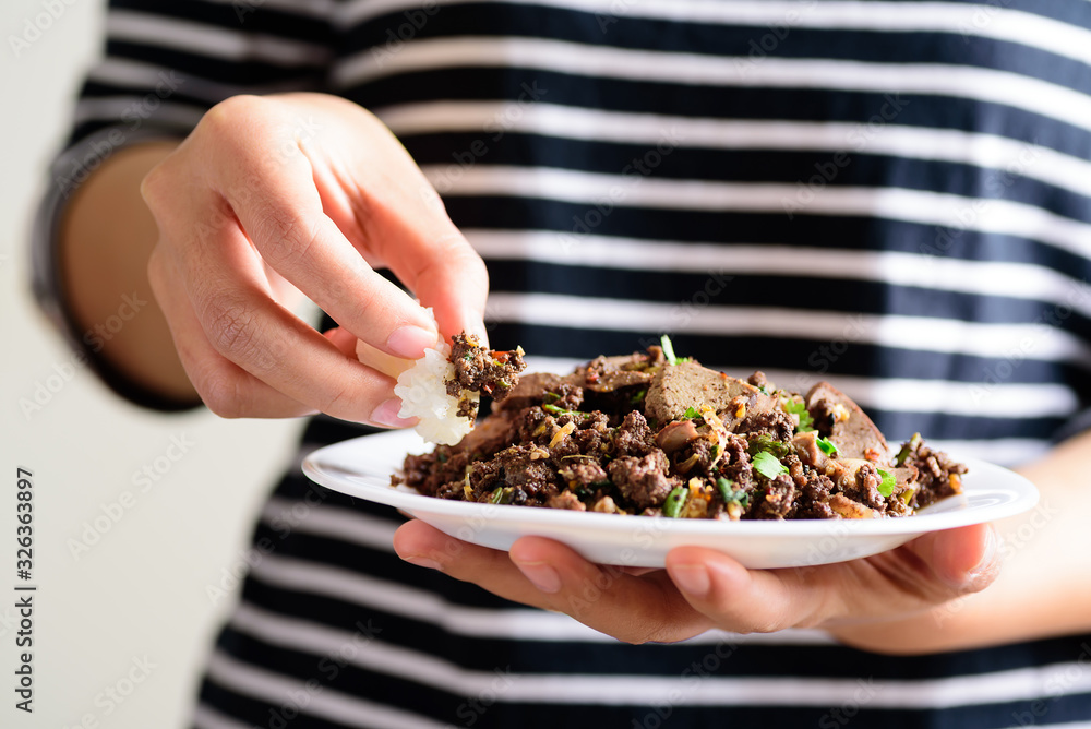 Traditional Northern Thai food, spicy minced pork salad (Larb Moo Kua) eating with sticky rice by hand Traditional Northern Thai food, spicy minced pork salad (Larb Moo Kua) eating with sticky rice by hand