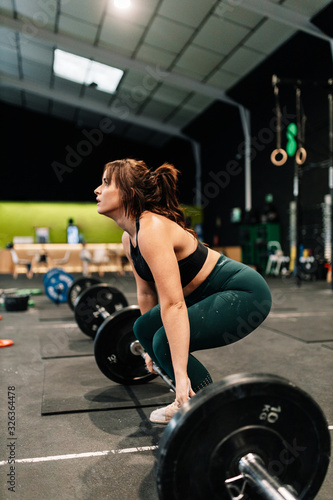 Strong female weight lifter preparing for lift in gym.