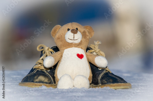 toybear leaning against babyshoes in snow photo