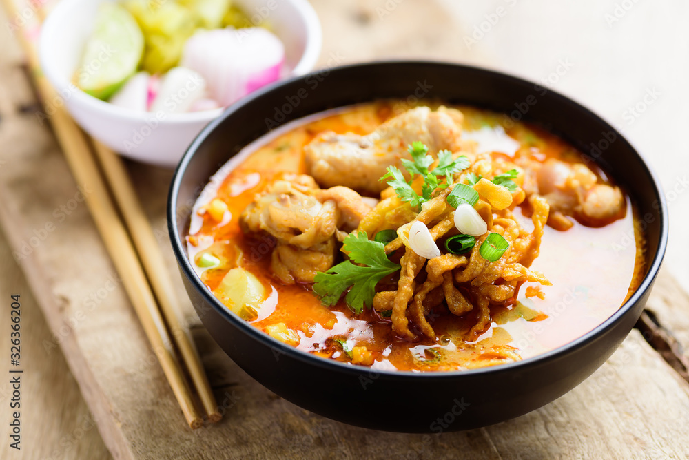 Traditional Northern Thai food (Khao Soi), spicy curry noodles soup with coconut milk and chicken in a bowl Traditional Northern Thai food (Khao Soi), spicy curry noodles soup with coconut milk and chicken in a bowl
