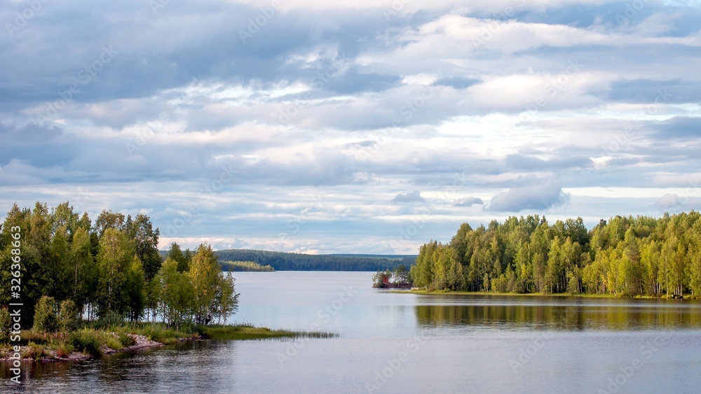 A fabulous landscape of a Finnish lake in the midst of a dense Scandinavian green forest. The concept of calm and quiet rest in the most environmentally friendly country.
