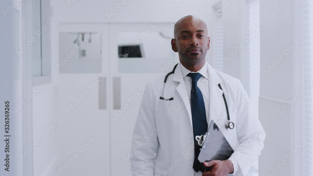 Portrait Of Mature Male Doctor Wearing White Coat Standing In Hospital Corridor Holding Clipboard Portrait Of Mature Male Doctor Wearing White Coat Standing In Hospital Corridor Holding Clipboard