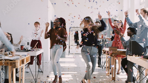 RED EPIC-W Happy young multiethnic female colleagues celebrate success with team and confetti at office slow motion.