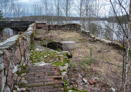 The ruins of an old house on the banks of a wide river on a cloudy spring day.