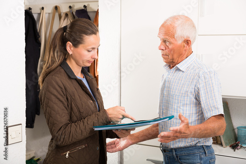 Fotografie Businesswoman trying to collect arrearages from erderly man at home door