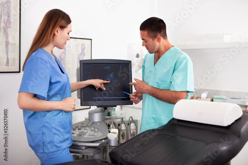 Two confident sonographers working together examining patient with modern ultrasound machine