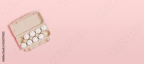 Happy Easter. White eggs with painted eyes in paper packaging on a pink background. Flat lay, top view, copy space. photo