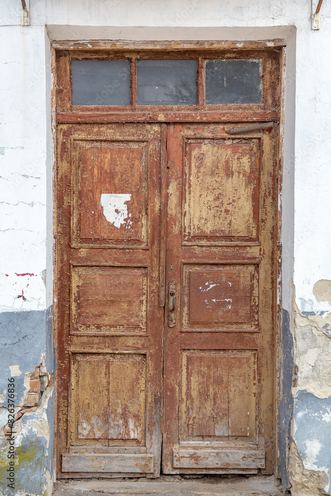 Vintage retro wooden door in legacy building with peeling old paint.