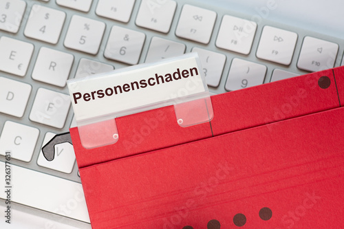 Roter Hängehefter mit Reiter und dem Text: Personenschaden. Der Ordner liegt auf einem Computer Keyboard photo