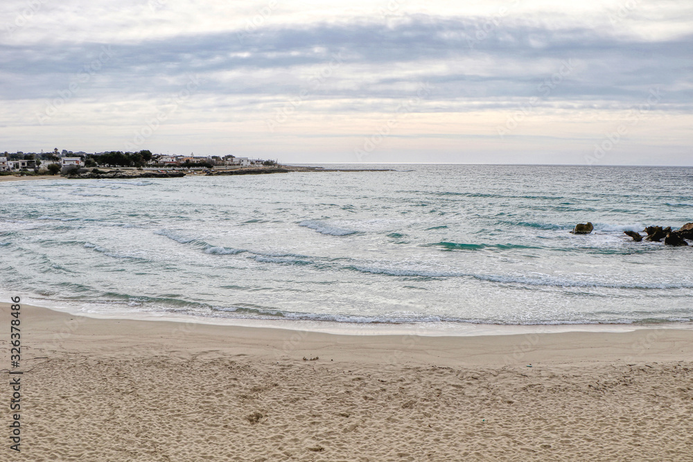 Beach in the middle of winter with cloudy sky on the coast of Taranto, Puglia, Italy
