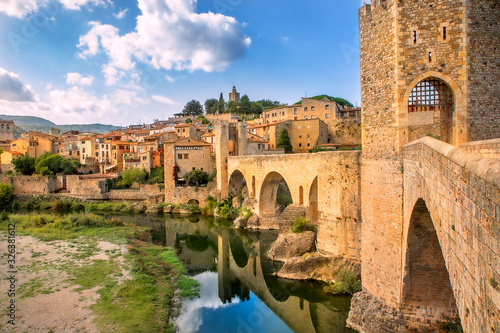 Besalu, Girona, Catalonia, Spain. Famous landmark. Old medieval Romanesque bridge Besalu over the river Fluvia on a sunny summer day. photo