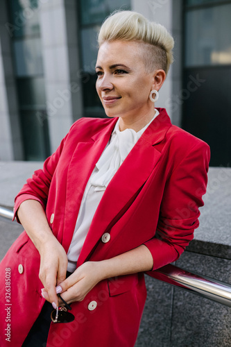 Beautiful girl in a red jacket smiles on the street