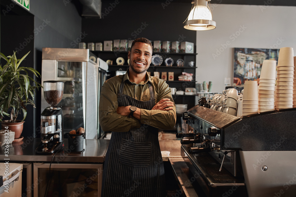 Portrait of a smiling confident young waiter standing at the cafe counter Portrait of a smiling confident young waiter standing at the cafe counter