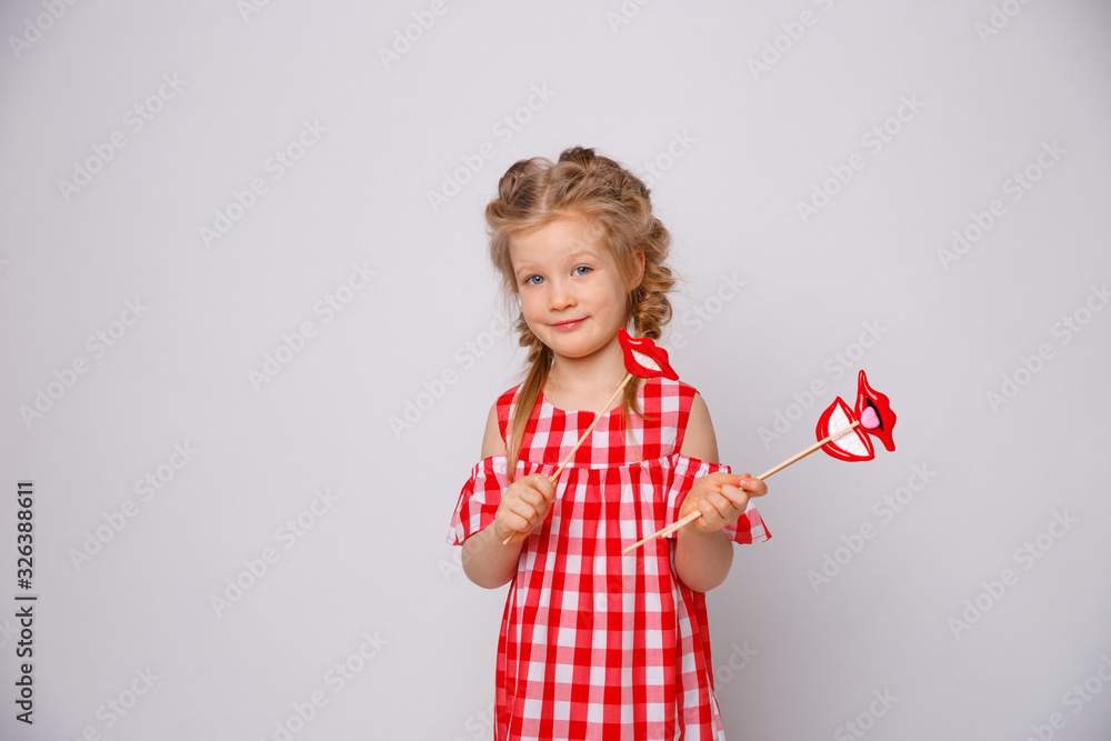 Funny smiling baby girl summer dress on white background . Baby girl with a lip accessory on a stick. Funny smiling baby girl summer dress on white background . Baby girl with a lip accessory on a stick.