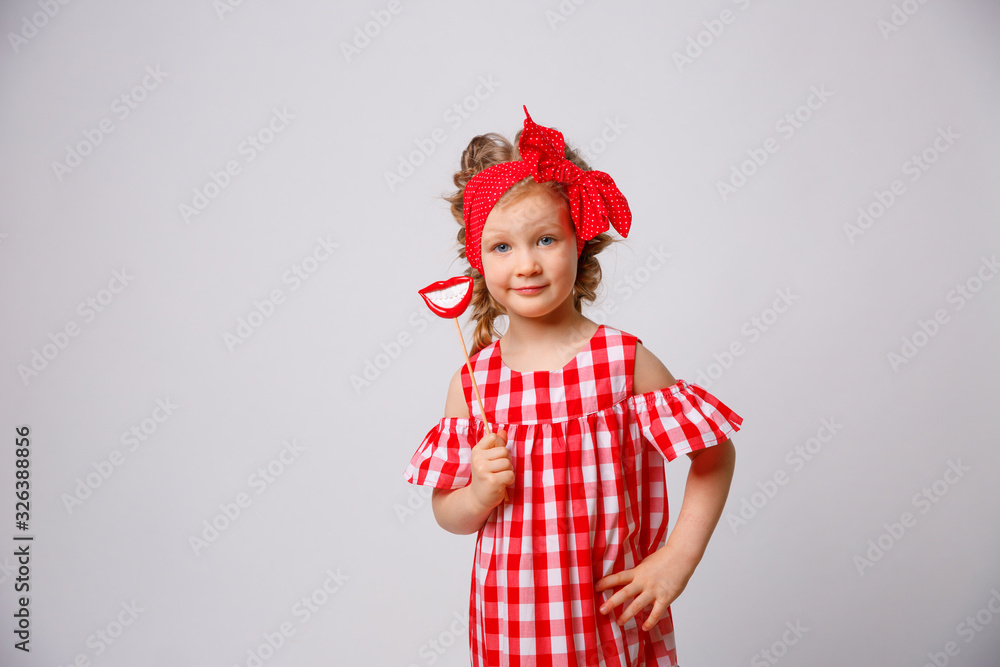 Funny smiling baby girl summer dress on white background . Baby girl with a lip accessory on a stick. Funny smiling baby girl summer dress on white background . Baby girl with a lip accessory on a stick.