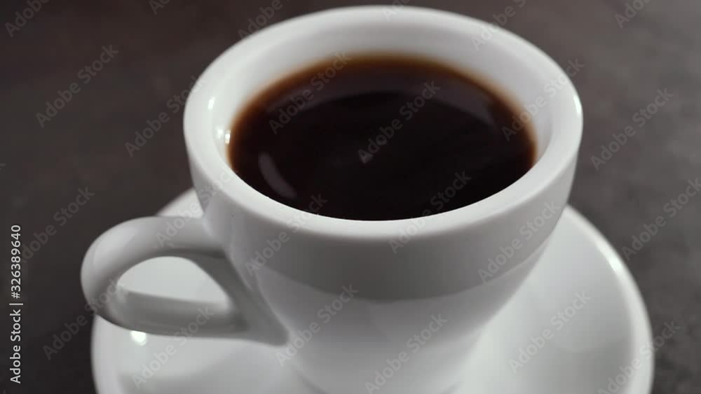 A drop of black coffee drips slowly into the coffee cup. A drop of black coffee drips slowly into the coffee cup.