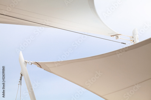 White awnings in sails shape under bright blue sky photo