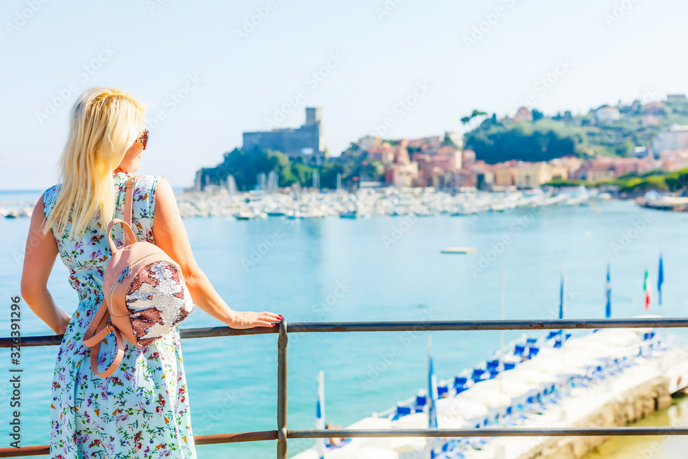 Monterosso young woman at the beach with dress, Chairs and umbrellas fill the spiaggia di fegina beach , the wide sandy beach village of Monterosso Italy, part of the Cinque Terre Italy