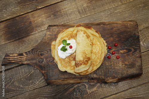 Flat lay tasty pancakes with sour cream and red berries on a wooden rustic background with copy space.  photo