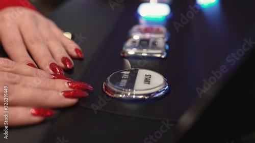 Woman's hand presses button on slot machine in casino