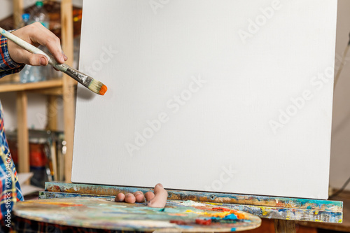 An artist of an art Studio next to an empty canvas layout. Art supplies for drawing