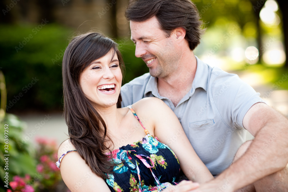 Happy Young Man and Woman Laughing While Sitting on Sidewalk Happy Young Man and Woman Laughing While Sitting on Sidewalk