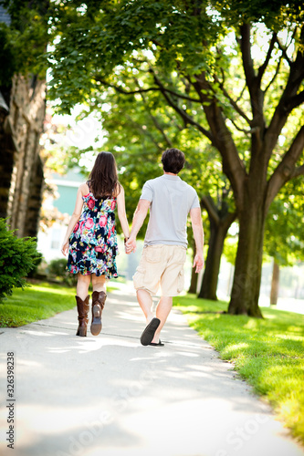 Young Couple Walking on Sidewalk in Neighborhood © IdeaBug, Inc.