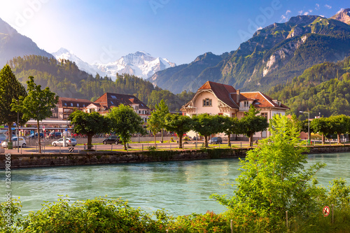 Train station and Aare river in Interlaken, important tourist center in Bernese Highlands, Switzerland. The Jungfrau is visible in background