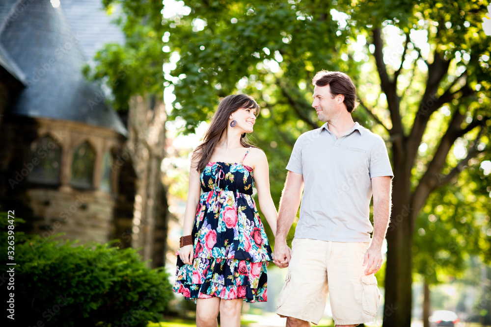 Happy Young Couple Walking on Sidewalk in Neighborhood Happy Young Couple Walking on Sidewalk in Neighborhood