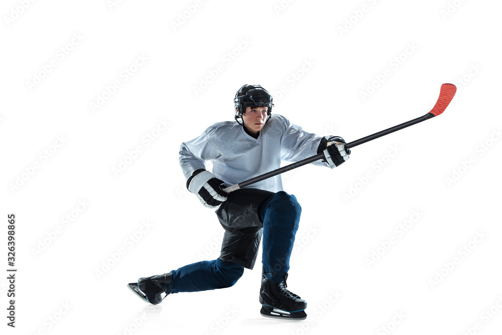 Serious. Young male hockey player with the stick on ice court and white background. Sportsman wearing equipment and helmet practicing. Concept of sport, healthy lifestyle, motion, movement, action. Serious. Young male hockey player with the stick on ice court and white background. Sportsman wearing equipment and helmet practicing. Concept of sport, healthy lifestyle, motion, movement, action.