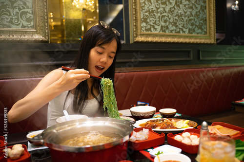 Asian woman eating vegetable noodles And the sukiyaki pot that is boiling in front