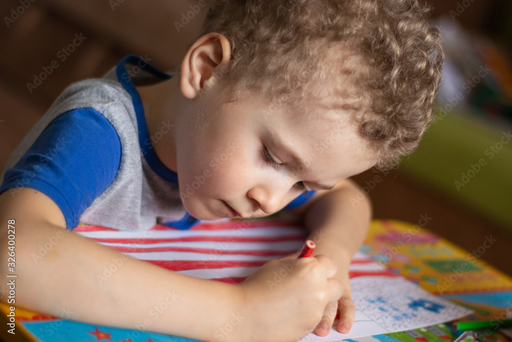 Little boy draws a USA flag. The boy colors the flag with crayons. Education, the study of state symbols, a photo. Little boy draws a USA flag. The boy colors the flag with crayons. Education, the study of state symbols, a photo.