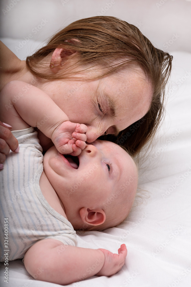Young mother playing with baby on bed. Motherhood, child and parenthood concept