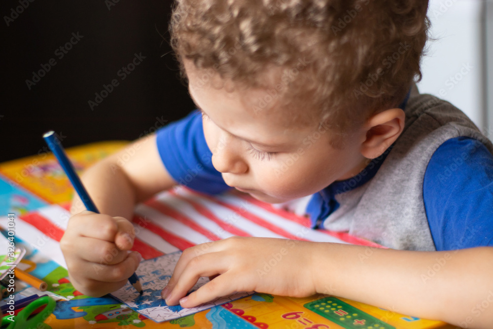 Little boy draws a USA flag. The boy colors the flag with crayons. Education, the study of state symbols, a photo. Little boy draws a USA flag. The boy colors the flag with crayons. Education, the study of state symbols, a photo.