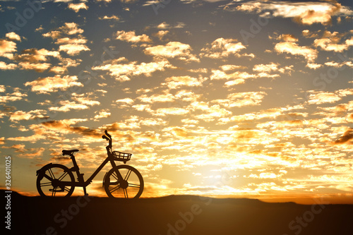 Silhouette of a bicycle against sunset background.