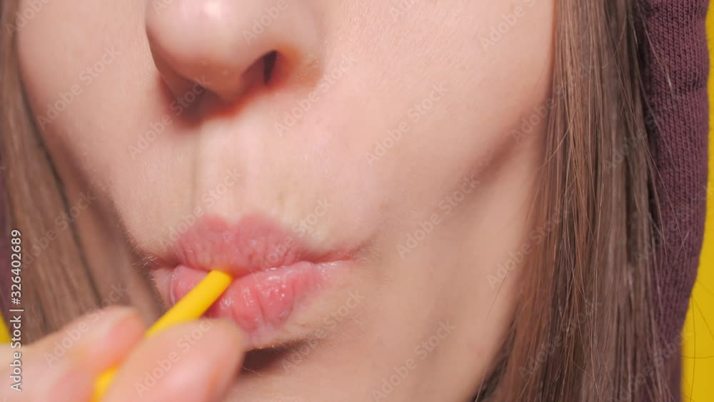 Close-up, female sexy lips suck a big yellow round lollipop. Copy space. yellow background Close-up, female sexy lips suck a big yellow round lollipop. Copy space. yellow background