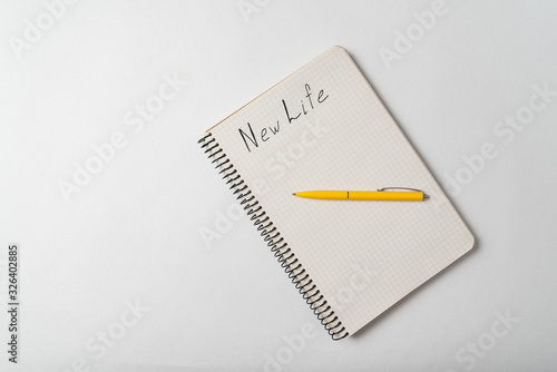 New Life motivation text on copybook. Notepad and pen on white background.