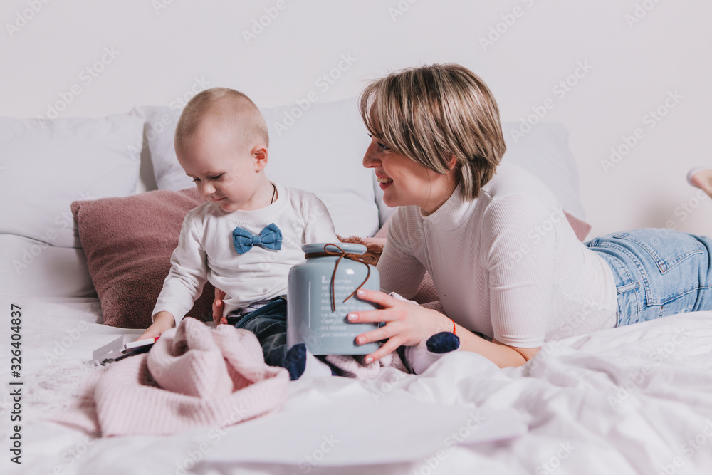 Young mother with her 1 years old little son playing with pencils in the bed Young mother with her 1 years old little son playing with pencils in the bed