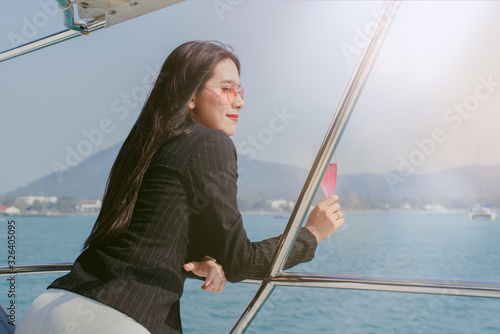 Woman holding a beautiful glass on the open deck of a cruise, business woman holding glass of wine in the yacht, Business woman looking out to the sea