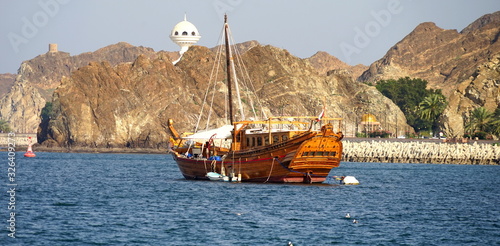 Hölzerne Dhau vor der Küste von Mutrah mit Bergen und Weihrauchbrenner im Hintergrund