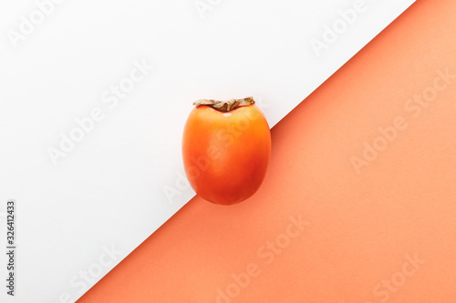 Top view of persimmon on white and orange background photo