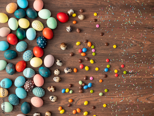 Colorful Easter eggs on wooden table with candies. Easter holiday decorations , Easter concept background.