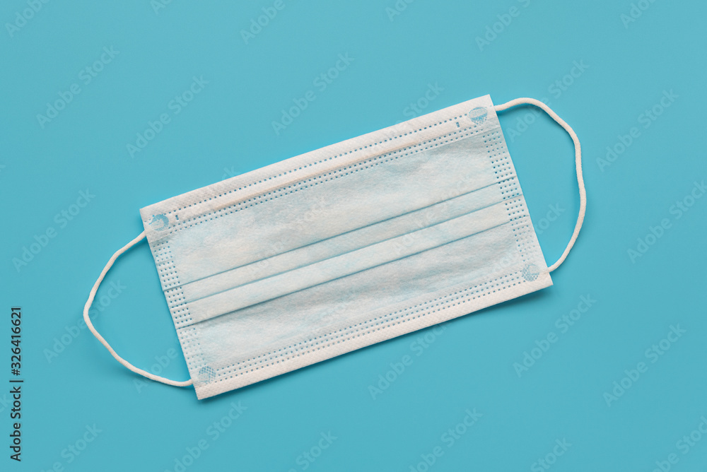 Surgical ear-loop mask on blue background. Top view. Protection concept Surgical ear-loop mask on blue background. Top view. Protection concept