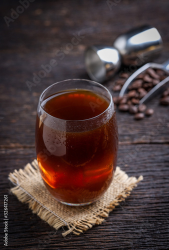 cold brew coffee into glass on wooden table.