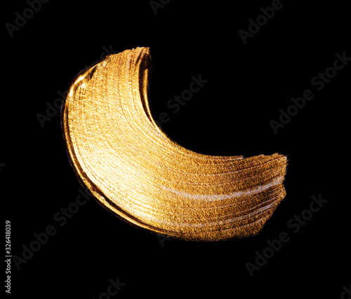 Creative brushstrokes of gold paint isolated on a black background. Gold paint texture.Acrylic gold paint. Smears of cosmetics, blush, highlighter, eye shadow, lipstick.