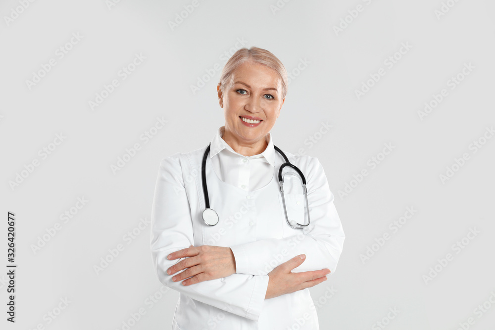 Portrait of mature doctor with stethoscope on light grey background Portrait of mature doctor with stethoscope on light grey background