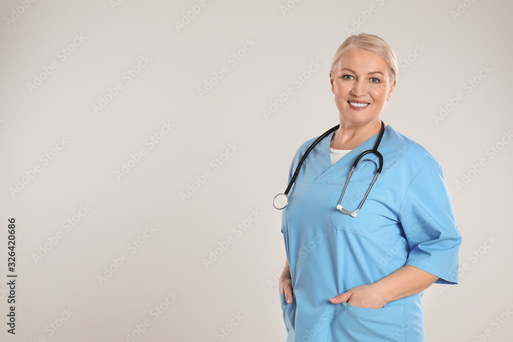 Portrait of mature doctor with stethoscope on light grey background. Space for text Portrait of mature doctor with stethoscope on light grey background. Space for text